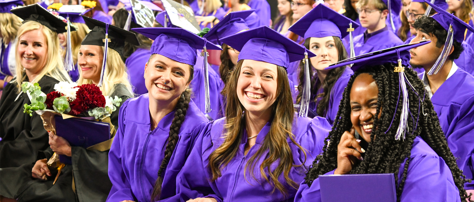 ACC students at 2026 Commencement wearing black and purple regalia and smiling for the camera.
