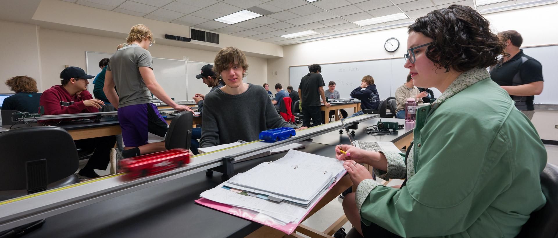 ACC students in a Physics class participating in an experiement with tracks and motorized cars at the Littleton Campus.