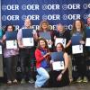 Members of ACC's OER team holding awards in front of Colorado OER logo wall