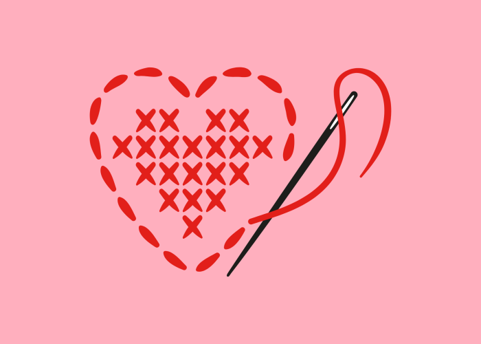 Needle and red thread cross-stiching a heart shape
