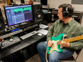 ACC faculty playing guitar in music audio tech lab