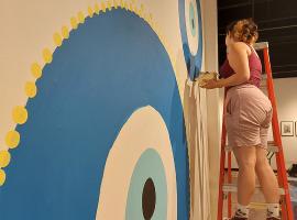 ACC student painting mural in the Colorado Gallery of the Arts