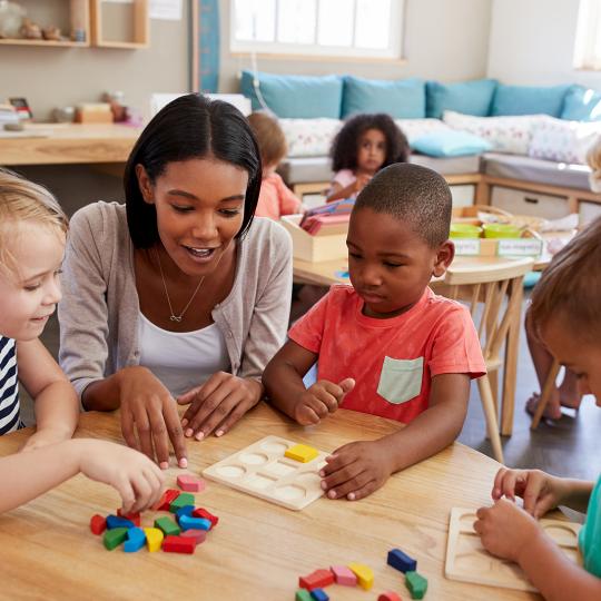 Early Childhood Education teacher with children around a table. 