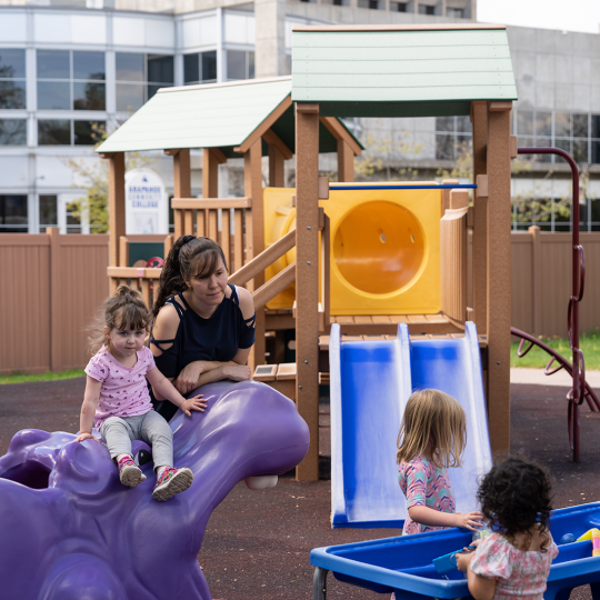 ACC Child Development Center teacher on the playground with children.